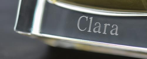 Gravure de parfum du nom "Clara" sur le fond d'un flacon de parfum en verre transparent.