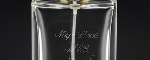 Gravure de parfum avec un message d'amour personnalisé sur un flacon de parfum en verre transparent.